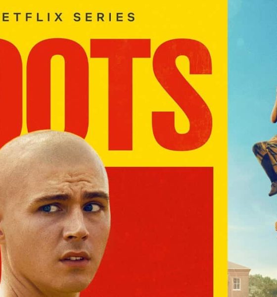 Cartaz da série Boots da Netflix. À esquerda, em destaque sobre um fundo amarelo e vermelho, está o título “BOOTS” em letras grandes e vermelhas. Abaixo do título, aparece o rosto de um jovem careca com expressão preocupada. À direita, três recrutas vestidos com calças camufladas e camisetas verdes participam de um treino militar, subindo cordas contra um céu azul.