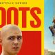 Cartaz da série Boots da Netflix. À esquerda, em destaque sobre um fundo amarelo e vermelho, está o título “BOOTS” em letras grandes e vermelhas. Abaixo do título, aparece o rosto de um jovem careca com expressão preocupada. À direita, três recrutas vestidos com calças camufladas e camisetas verdes participam de um treino militar, subindo cordas contra um céu azul.